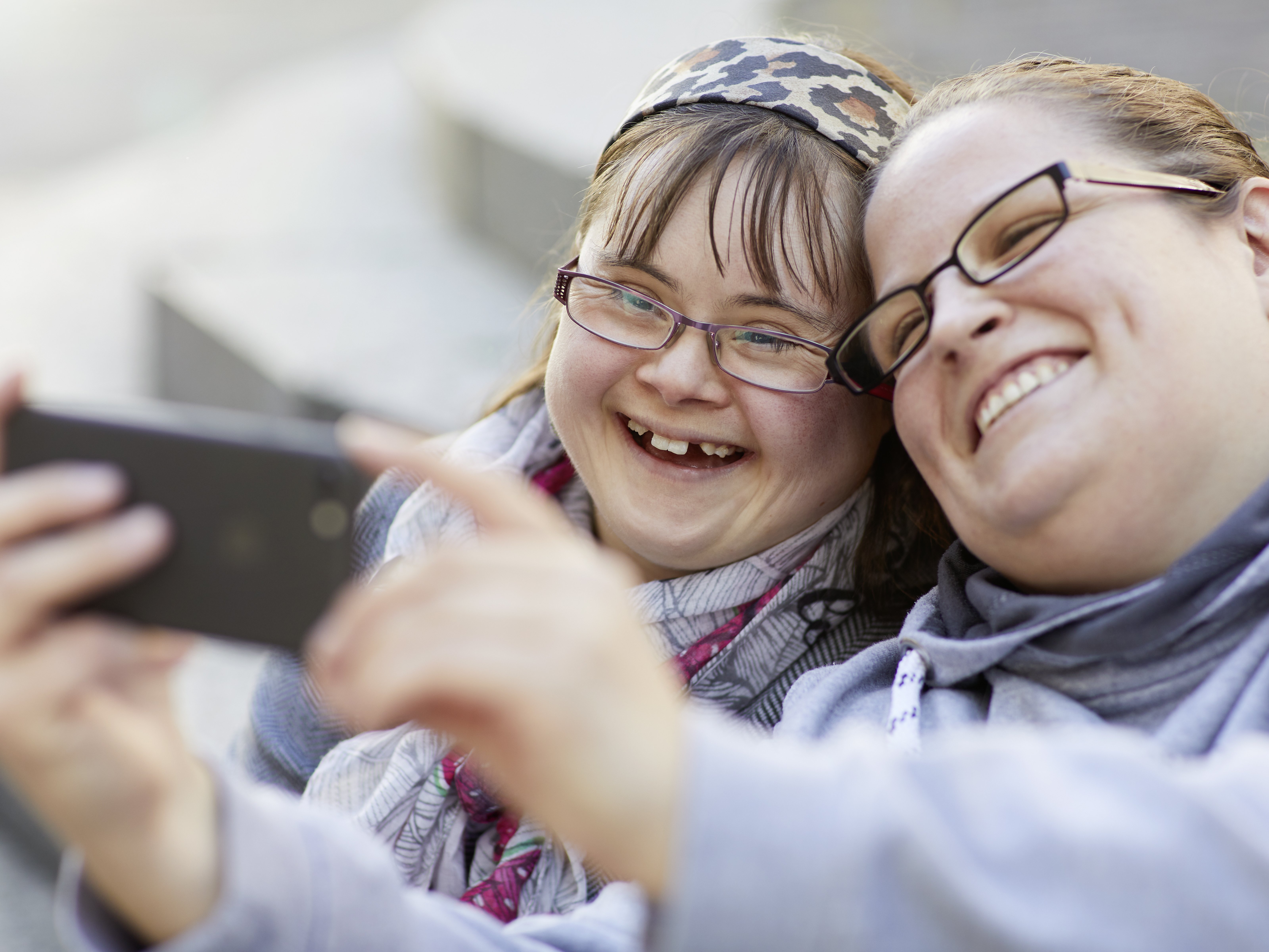 Foto von zwei jungen Frauen, die etwas auf einem Smartphone betrachten.